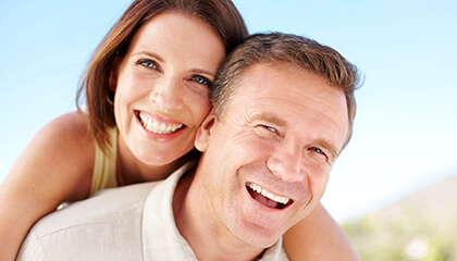 Older couple smiling broadly in sunshine