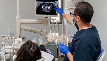 Dentist in navy scrubs showing patient her X-rays
