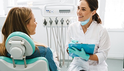 Dentist smiling while taking notes on clipboard