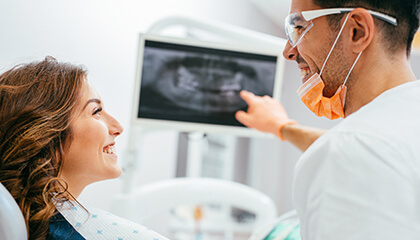 Female patient and dentist examine x-ray