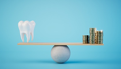 a stack of coins next to a model of a tooth