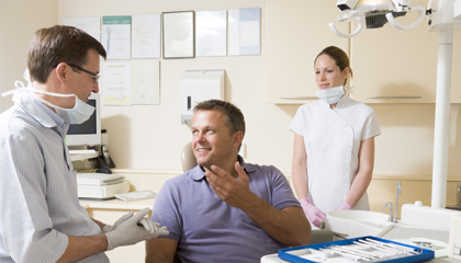 Smiling man in dental chair talking to dentist