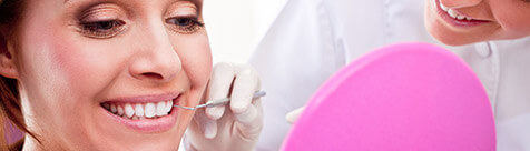 Young woman and dentist examine smile in mirror