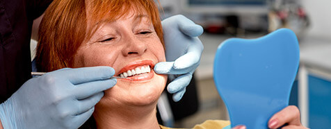 Older female patient assesses smile in mirror