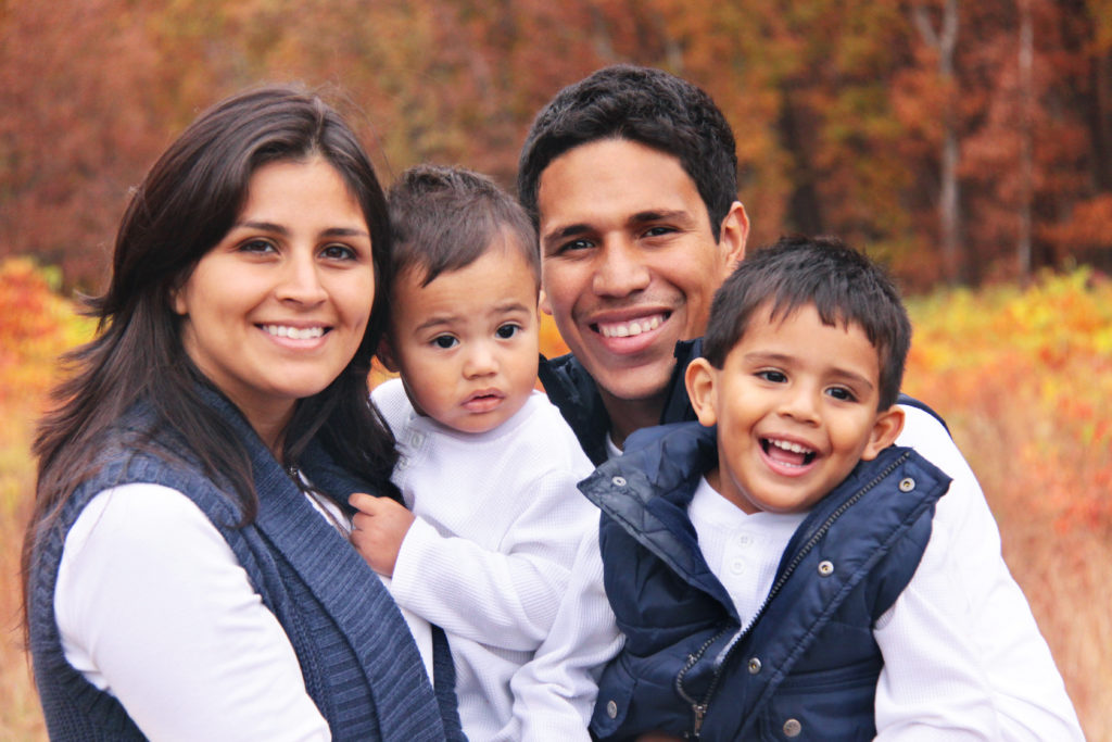 family of four hugging smiling