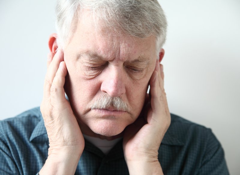 older man holding jaw in pain