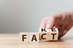 letter blocks spelling out "fact" and "fake"