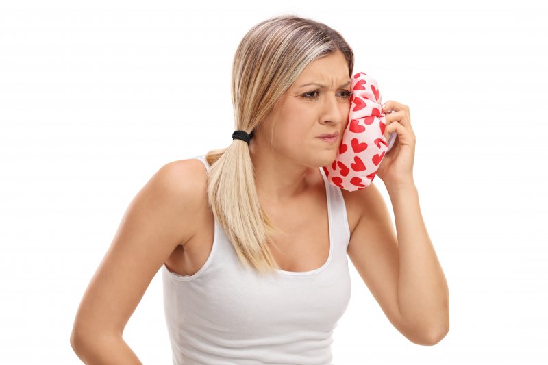 woman holding icepack to jaw