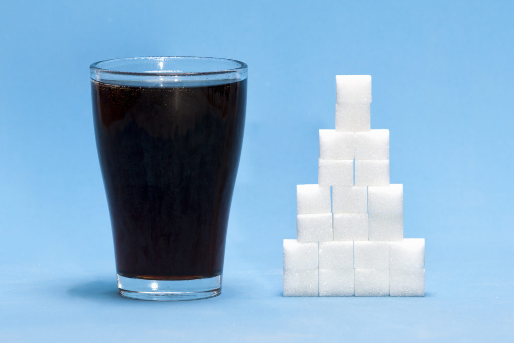 glass of soda beside sugar cubes