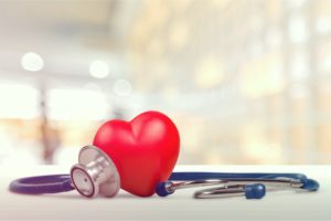 Red heart shape sitting on a table next to a stethoscope 