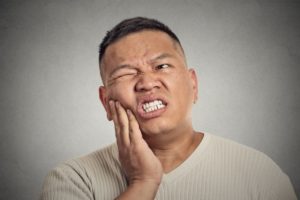 Pained man with hand on cheek needs his Melbourne emergency dentist