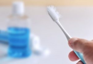 Person holding a used toothbrush with damaged bristles