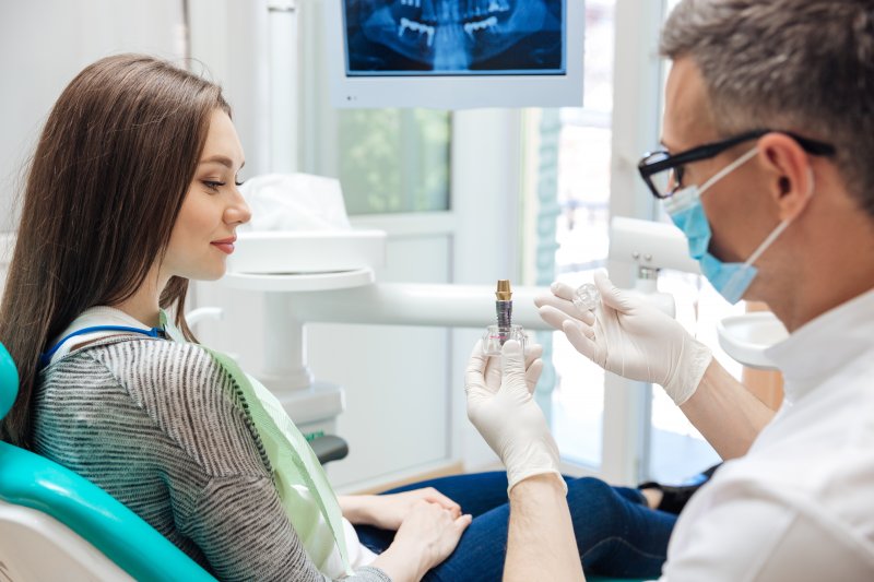 dentist in Melbourne showing patient a dental implant