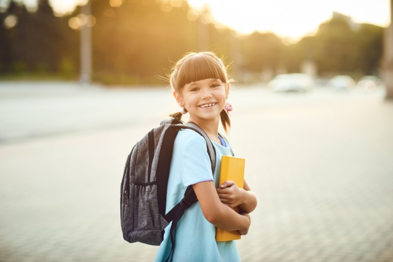 A young smiling girl wearing a backpack