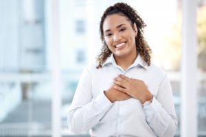 a woman smiling and placing her hand over her heart