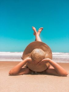 Woman in hat laying on beach