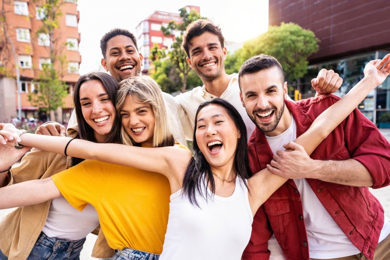 Group of young people smiles at camera in city.