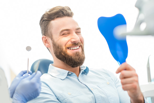 man smiling in dental mirror during checkup 