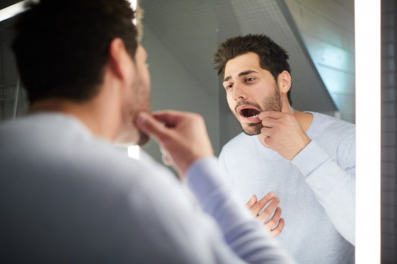 a man checking his teeth for food and debris