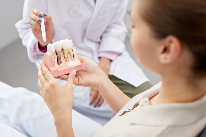 A dentist showing an implant model to his patient